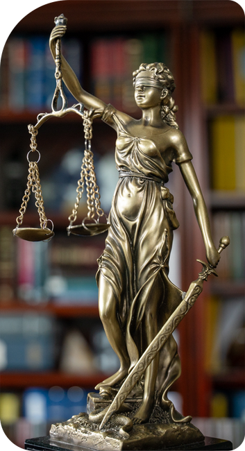 Statue of Lady Justice with scales and sword, blindfolded, in front of a bookshelf.