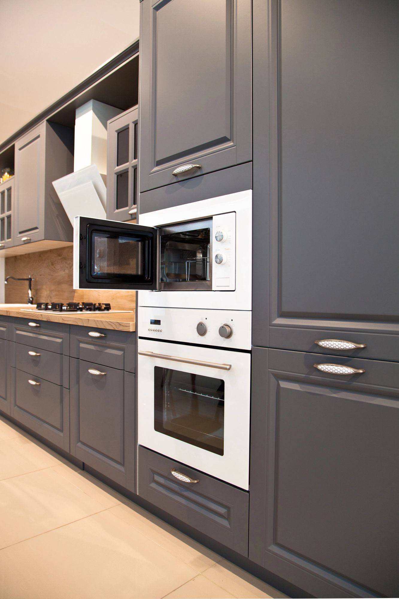 Modern dark gray kitchen with built-in oven, microwave, and wood countertops