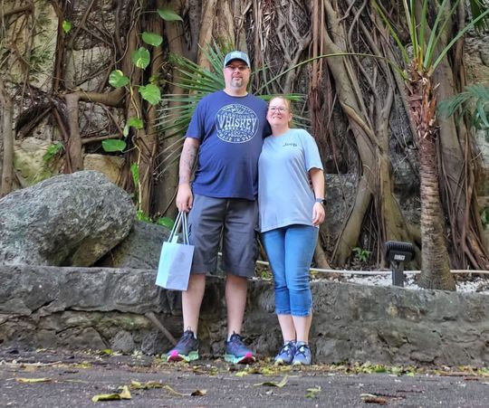 A man and a woman are posing for a picture in front of a tree.