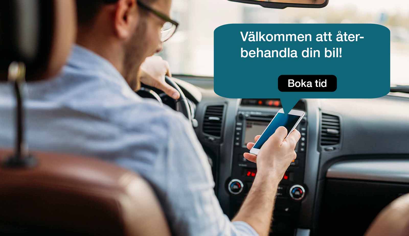 A man is sitting in a car looking at his phone.