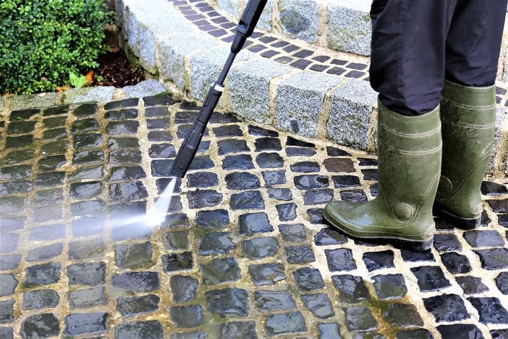 A Person is Using a High Pressure Washer — Land to Mow Garden Services Wagga In Wagga Wagga, NSW