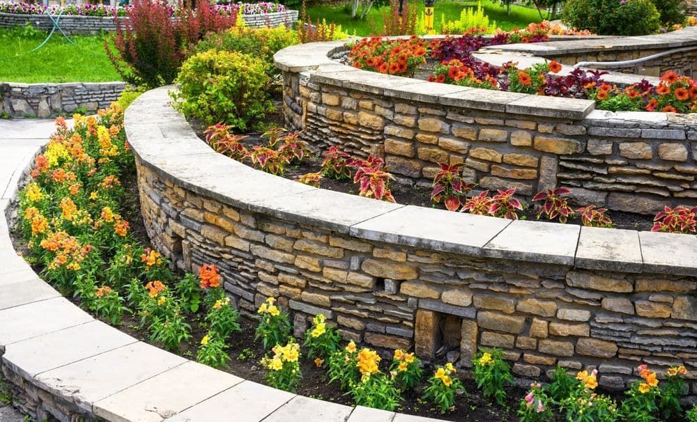 A Stone Wall With Flowers Growing on It in a Garden — Land to Mow Garden Services Wagga In Wagga Wagga, NSW