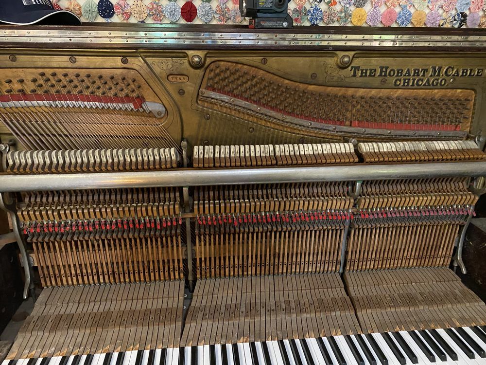 Inside view of an old, open piano, revealing strings, hammers, and the brand name 