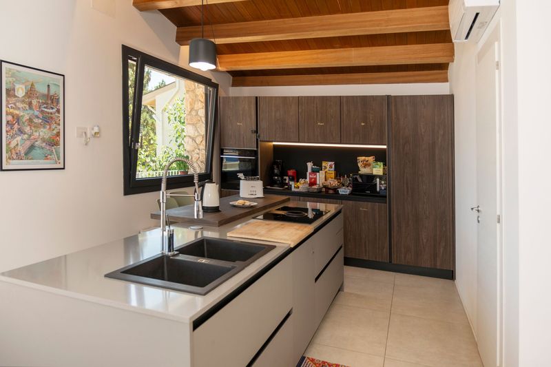 Cucina e soggiorno moderni a pianta aperta con ampie porte scorrevoli in vetro che si aprono su un balcone.