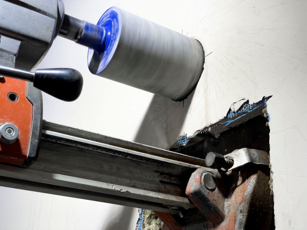 A Core Drill in Action, Creating a Large Hole in A White Wall — Ultra Services Ground Pavement & Building in Abercrombie, NSW