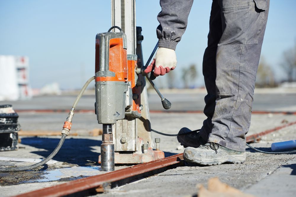 Person Using a Drill to Bore Into a Concrete Surface — Ultra Services Ground Pavement & Building in Parkes, NSW