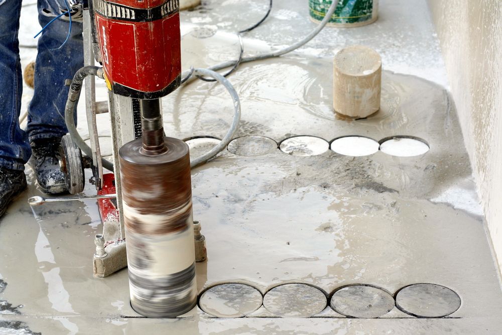 A Worker Using a Core Drill to Cut Holes in A Concrete Surface — Ultra Services Ground Pavement & Building in Mudgee, NSW