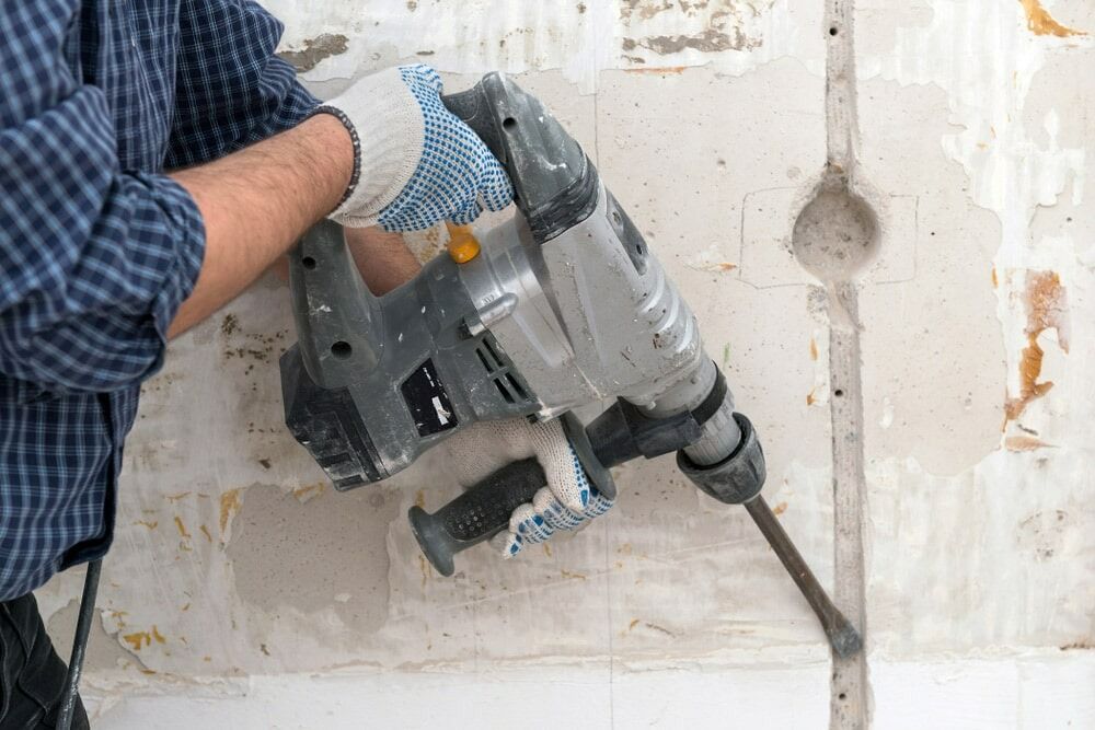 Person Using a Jackhammer to Break Through a Wall — Ultra Services Ground Pavement & Building in Abercrombie, NSW