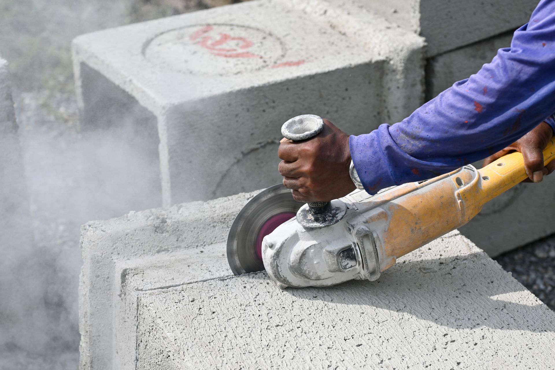 Person Using an Angle Grinder to Cut Concrete Blocks — Ultra Services Ground Pavement & Building in Parkes, NSW