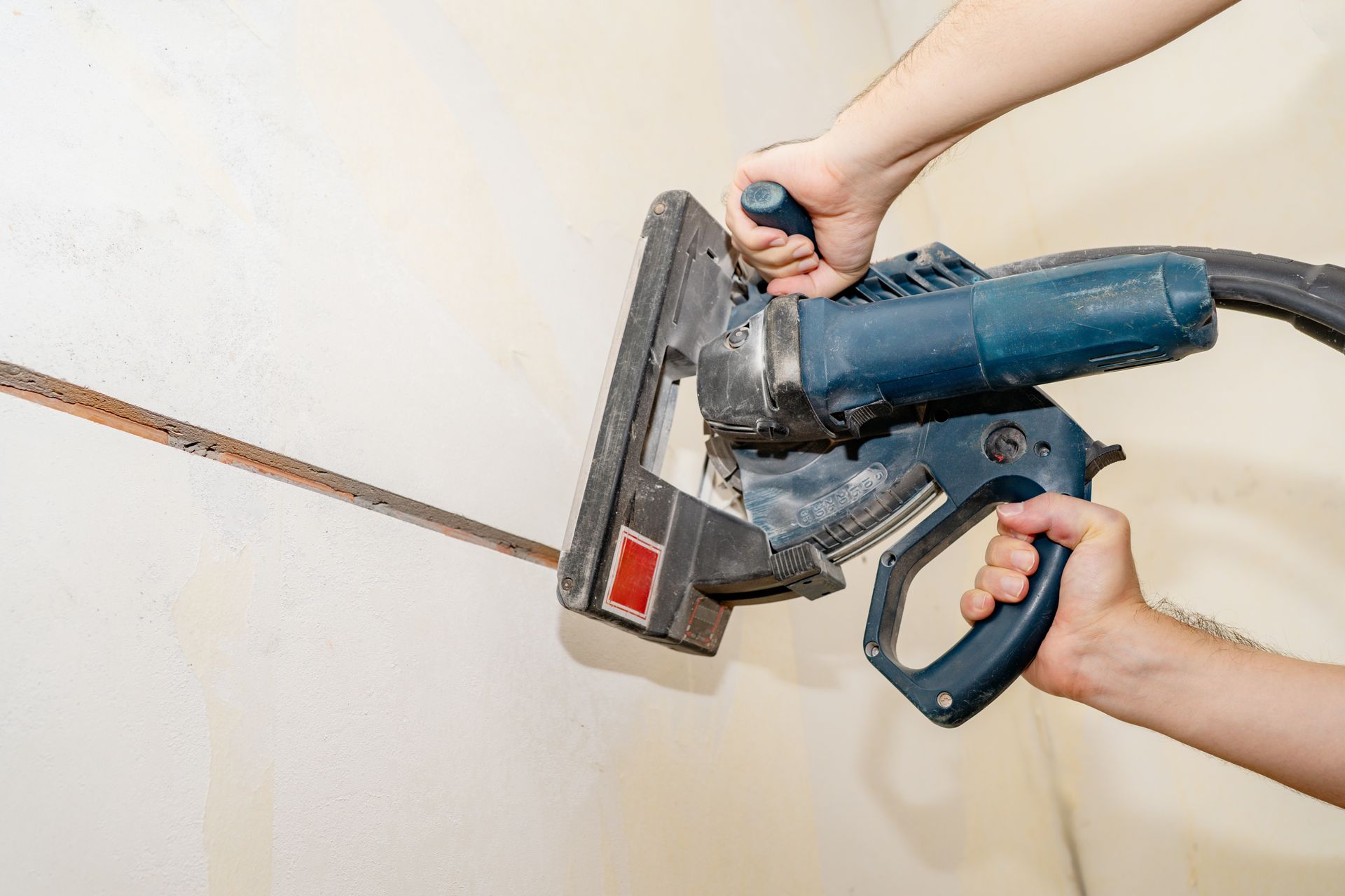 Person Using a Wall Chaser to Cut a Channel Into a Plaster Wall — Ultra Services Ground Pavement & Building in Orange, NSW