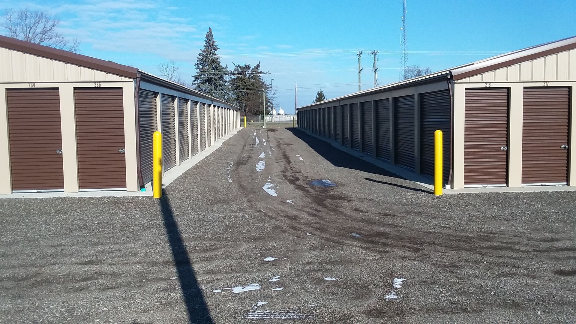 A row of storage units are lined up next to each other on a gravel road.