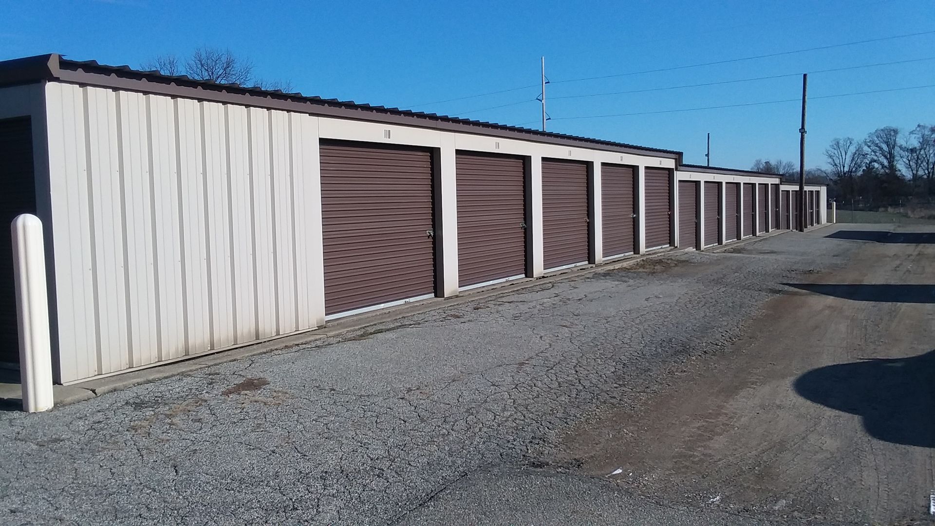 A row of storage units with brown doors on a gravel road