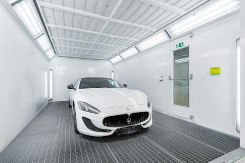 White car inside a brightly lit paint booth.