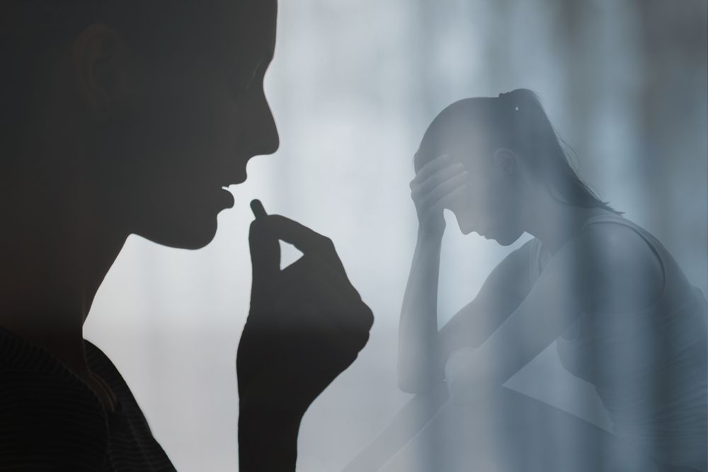 A silhouette of someone taking a pill, superimposed over a person sitting with their head in their hands.