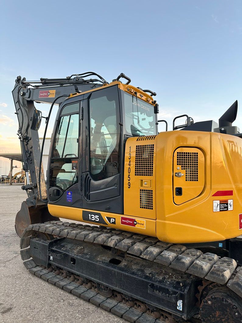 A yellow excavator is parked in a parking lot.
