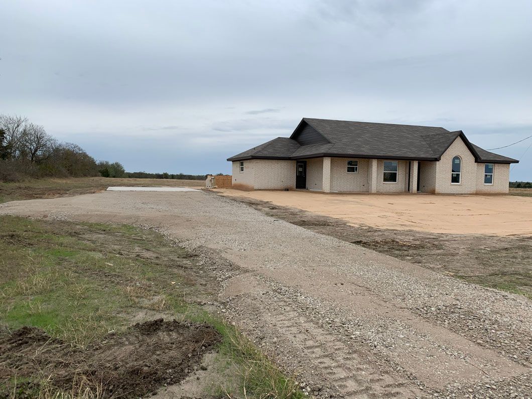 A house is sitting on top of a dirt road in the middle of a field.