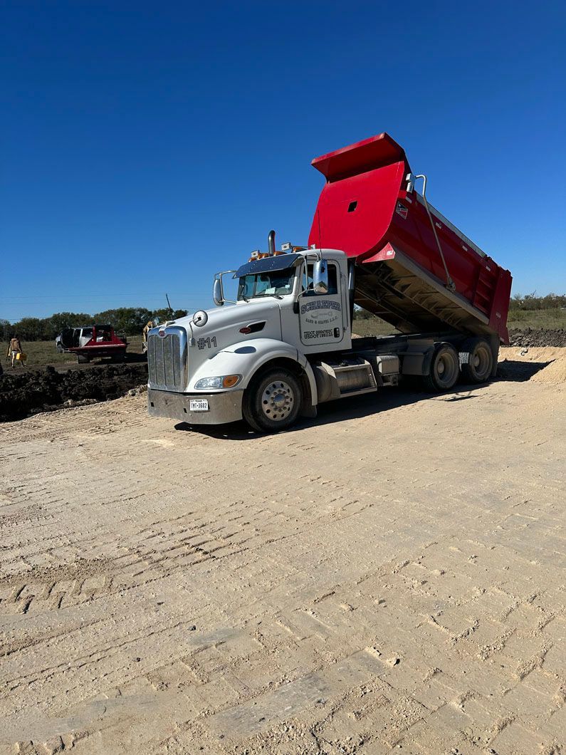 A dump truck is parked on a dirt road.