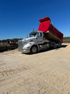 A dump truck is parked on a dirt road.