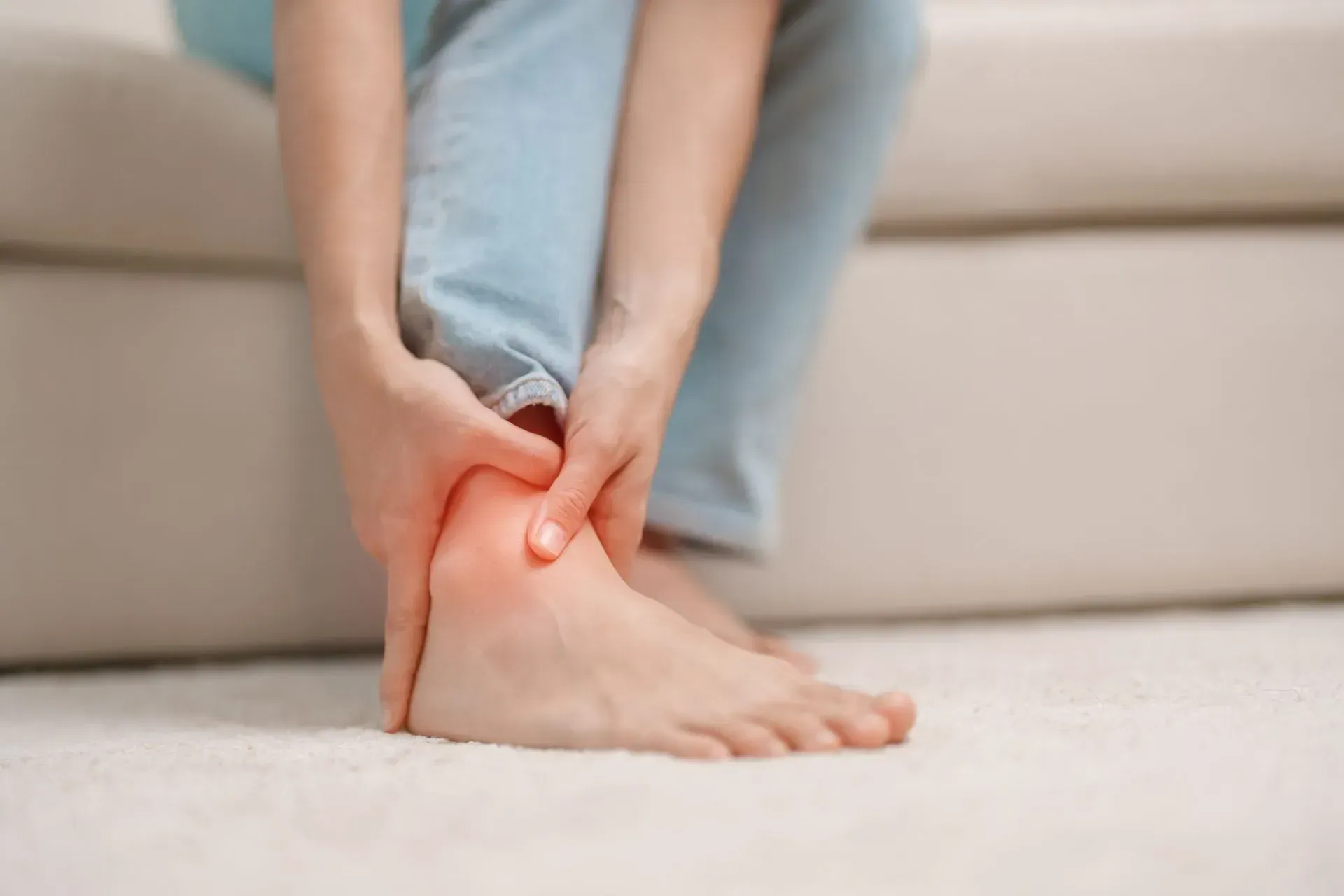 Person holding ankle, highlighting pain, redness indicated.