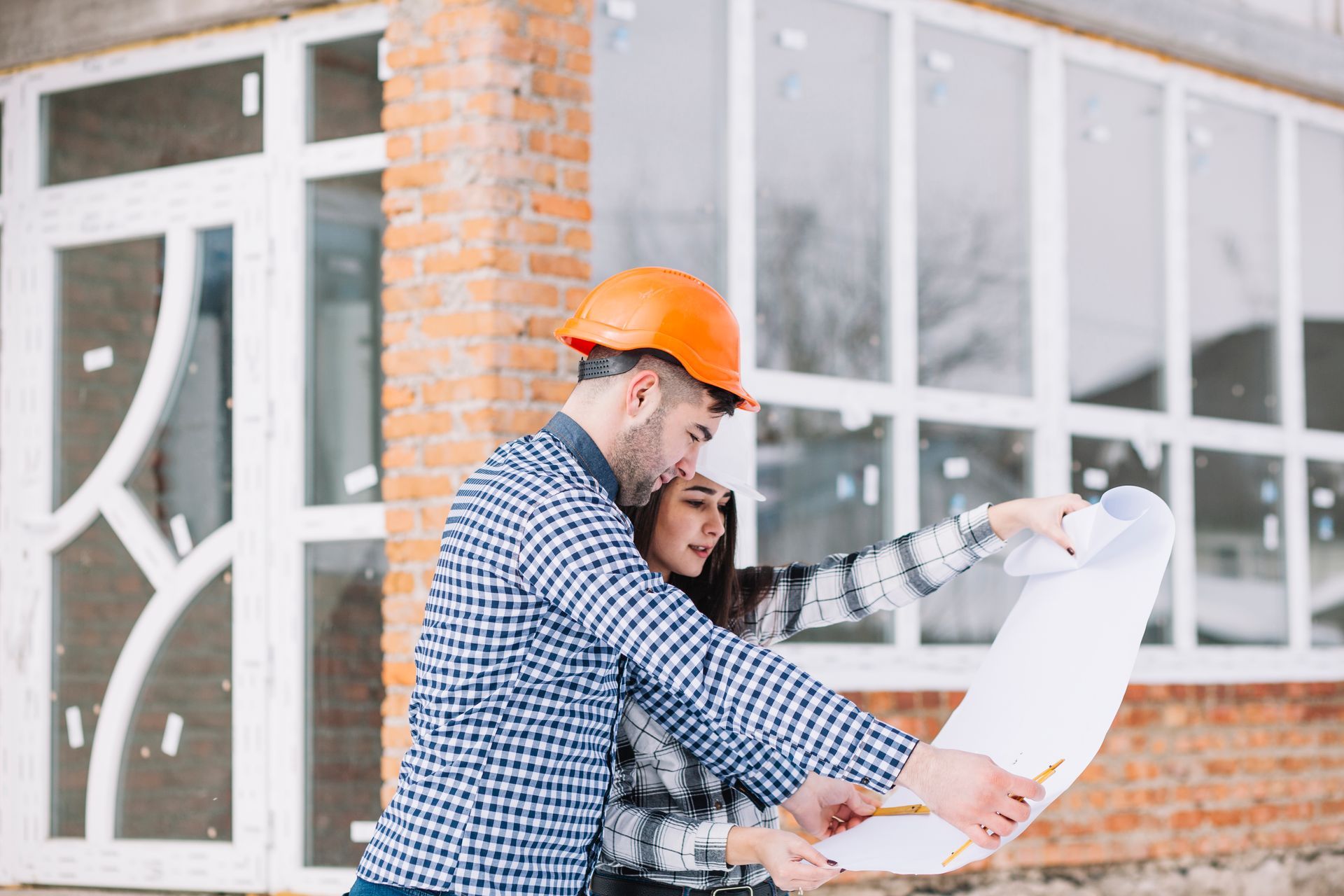 Deux personnes portant des casques de chantier examinent des plans sur un chantier de construction.