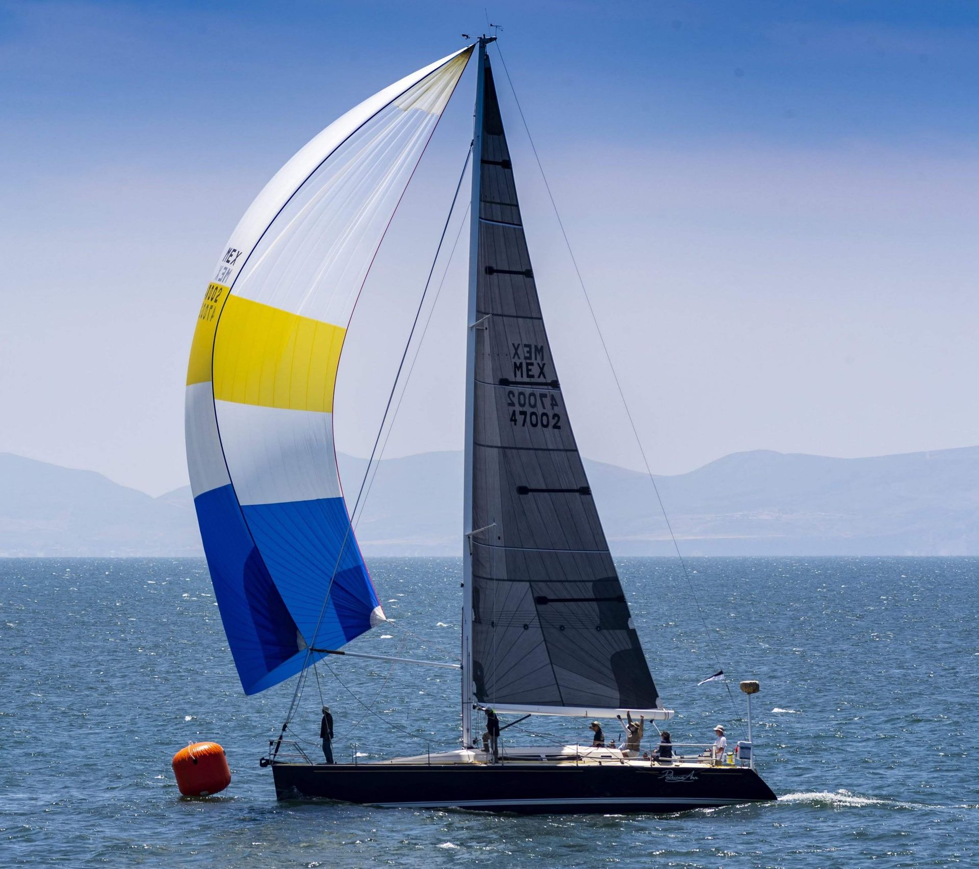 White sailboat on calm turquoise water under a blue sky with light clouds