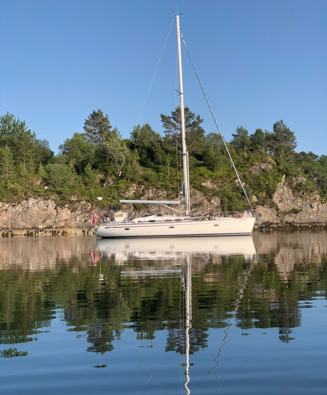 White sailboat on calm turquoise water under a blue sky with light clouds