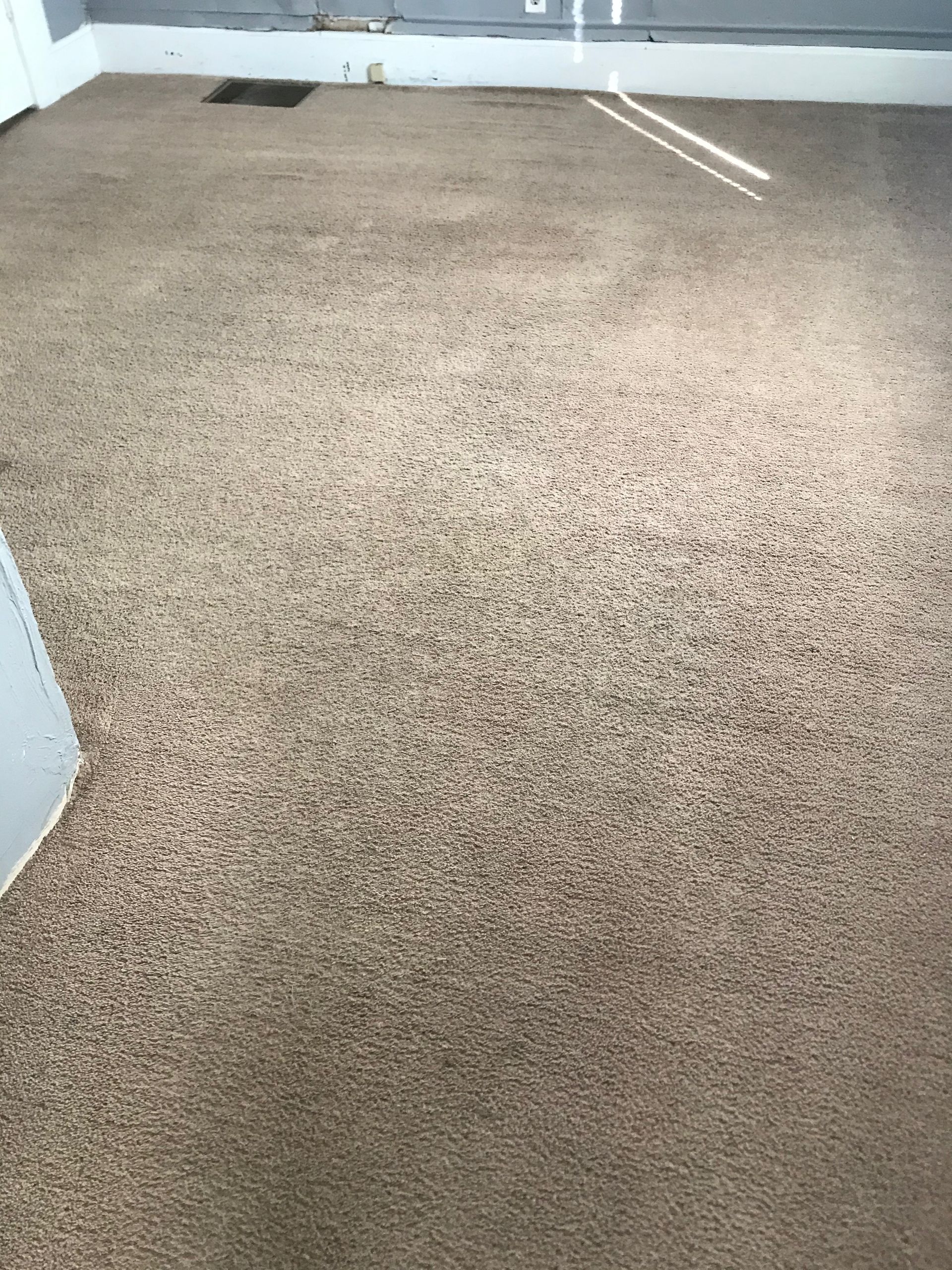 A room with a carpeted floor and a white wall.