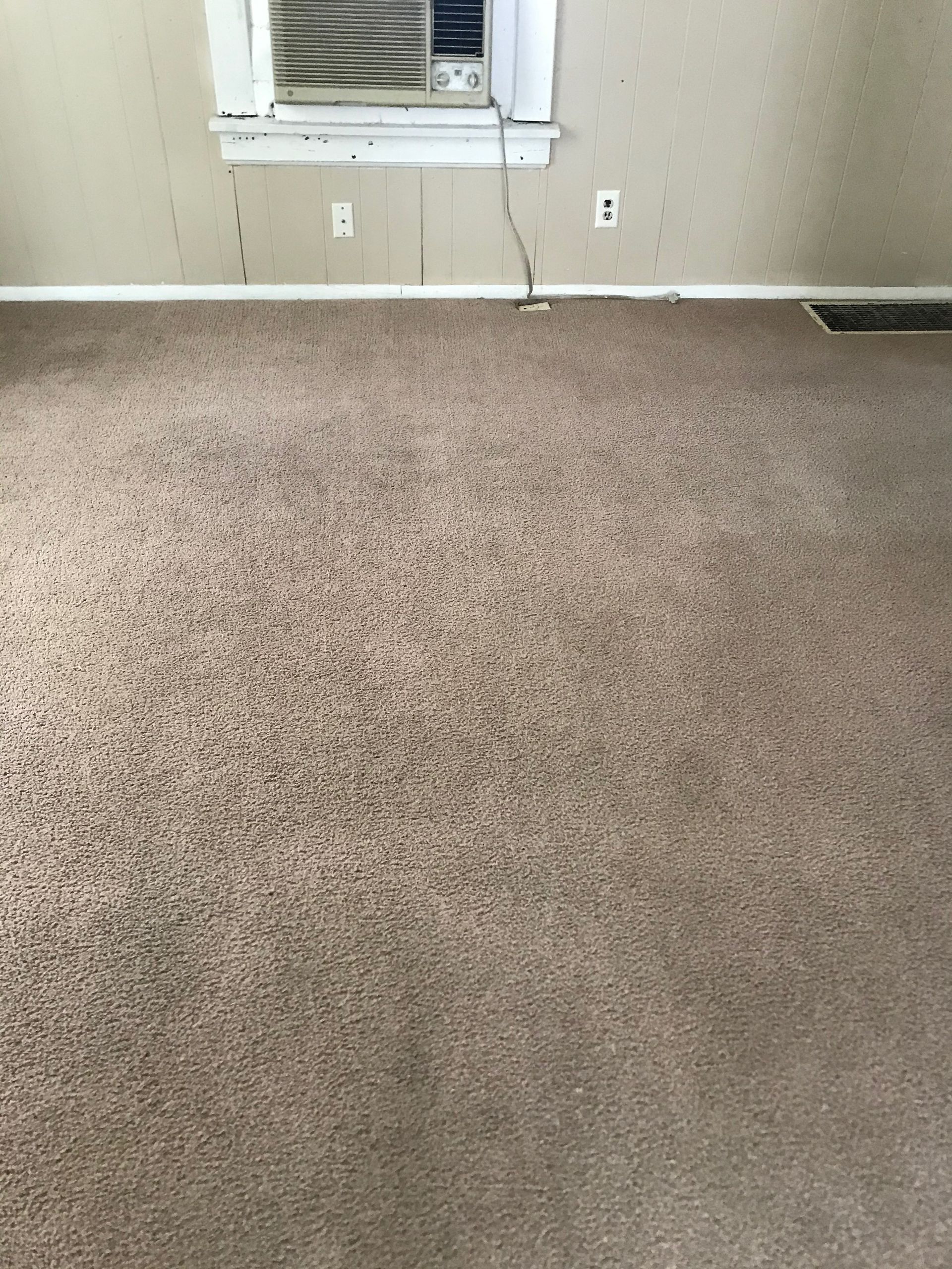 There is a window air conditioner in the corner of the room.