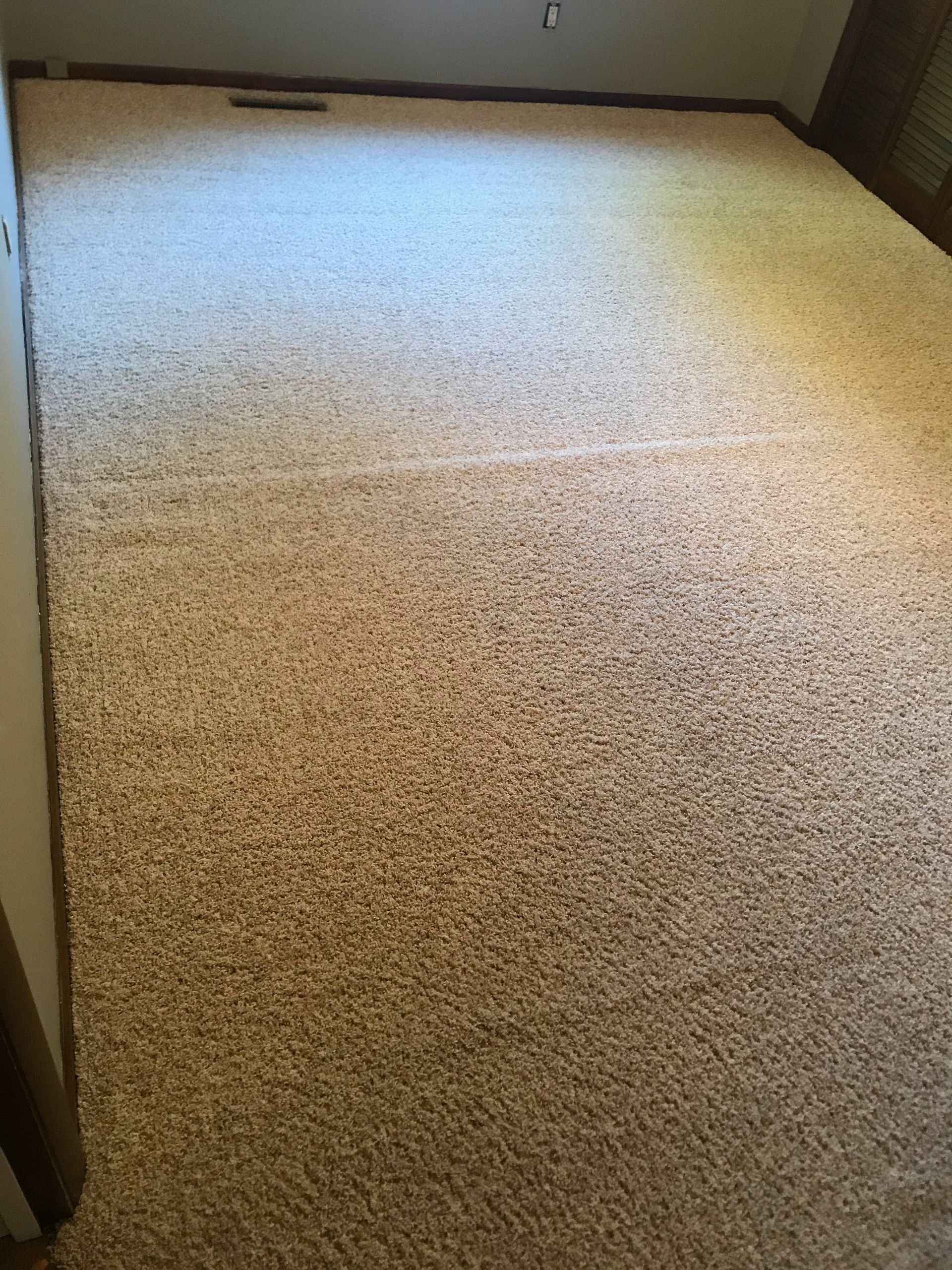 A large carpeted floor in a room with a window.