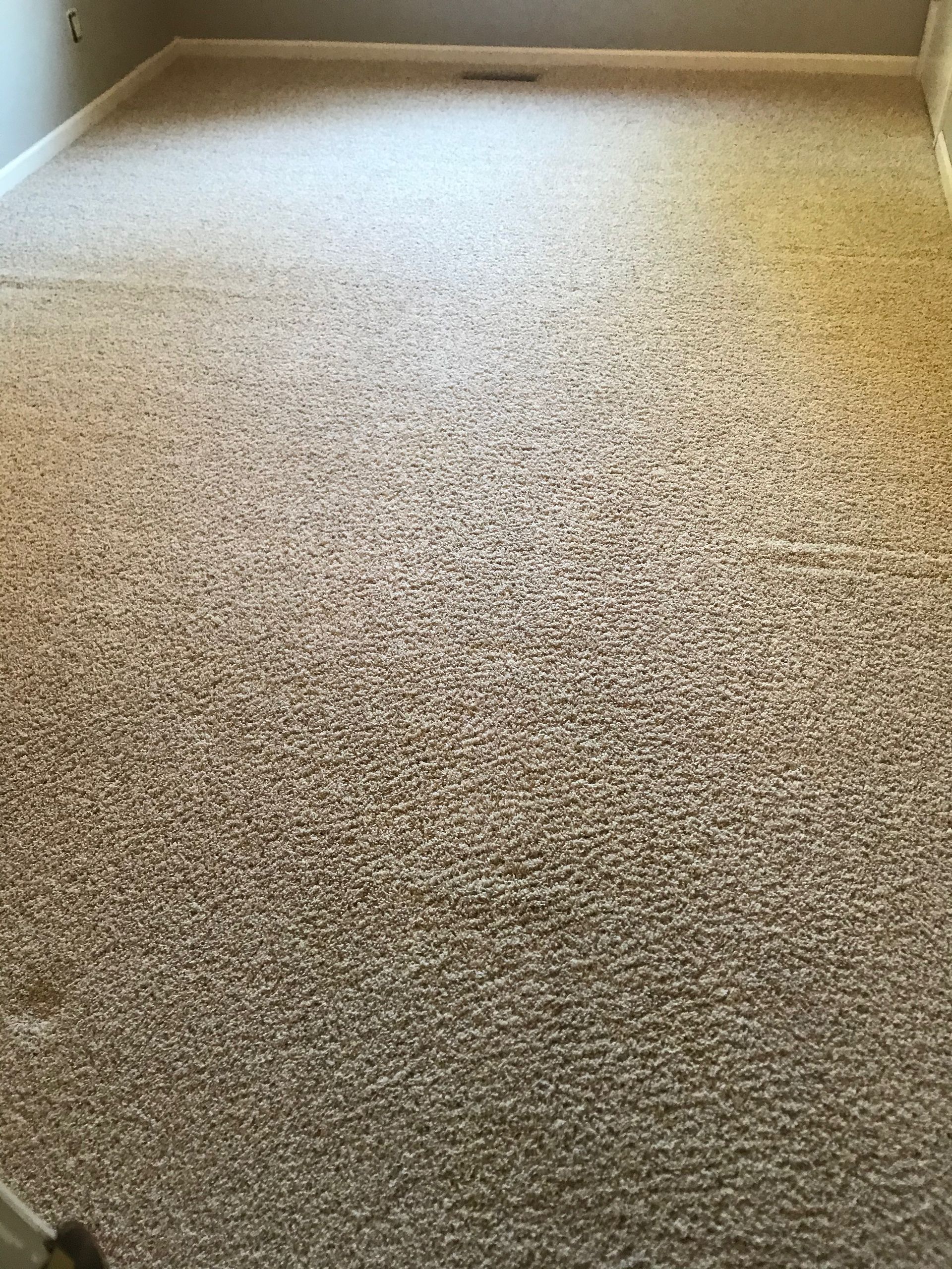 A large carpeted floor in a room with a staircase.