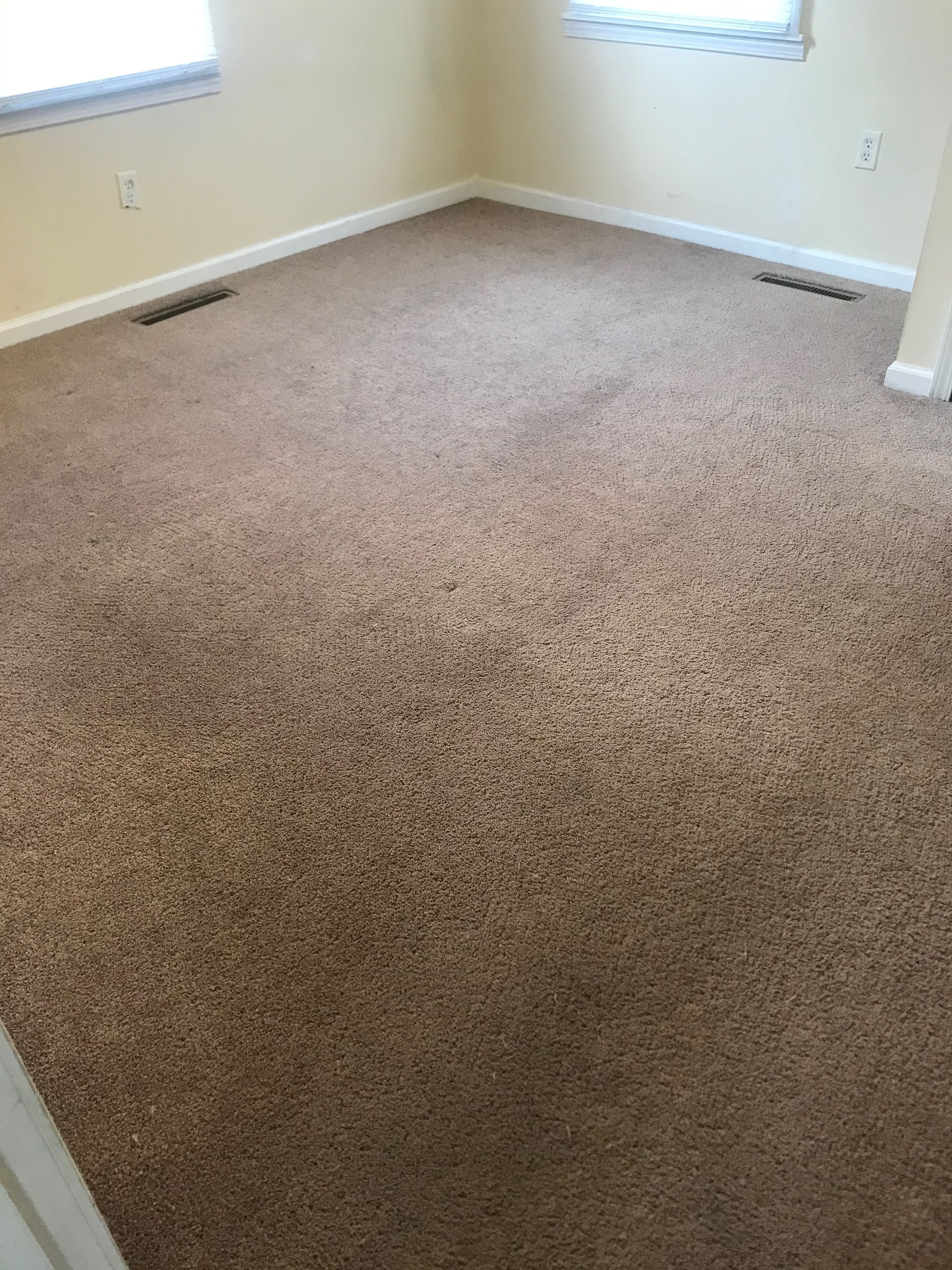 A bedroom with a large carpeted floor and a window.