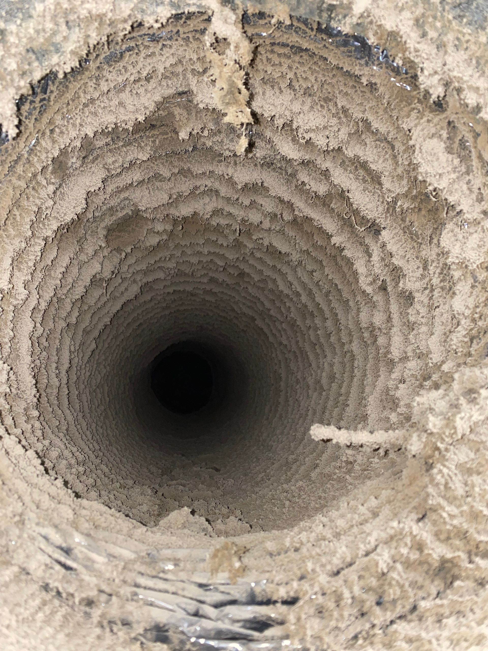 A close up of a dirty drain with a hole in the middle