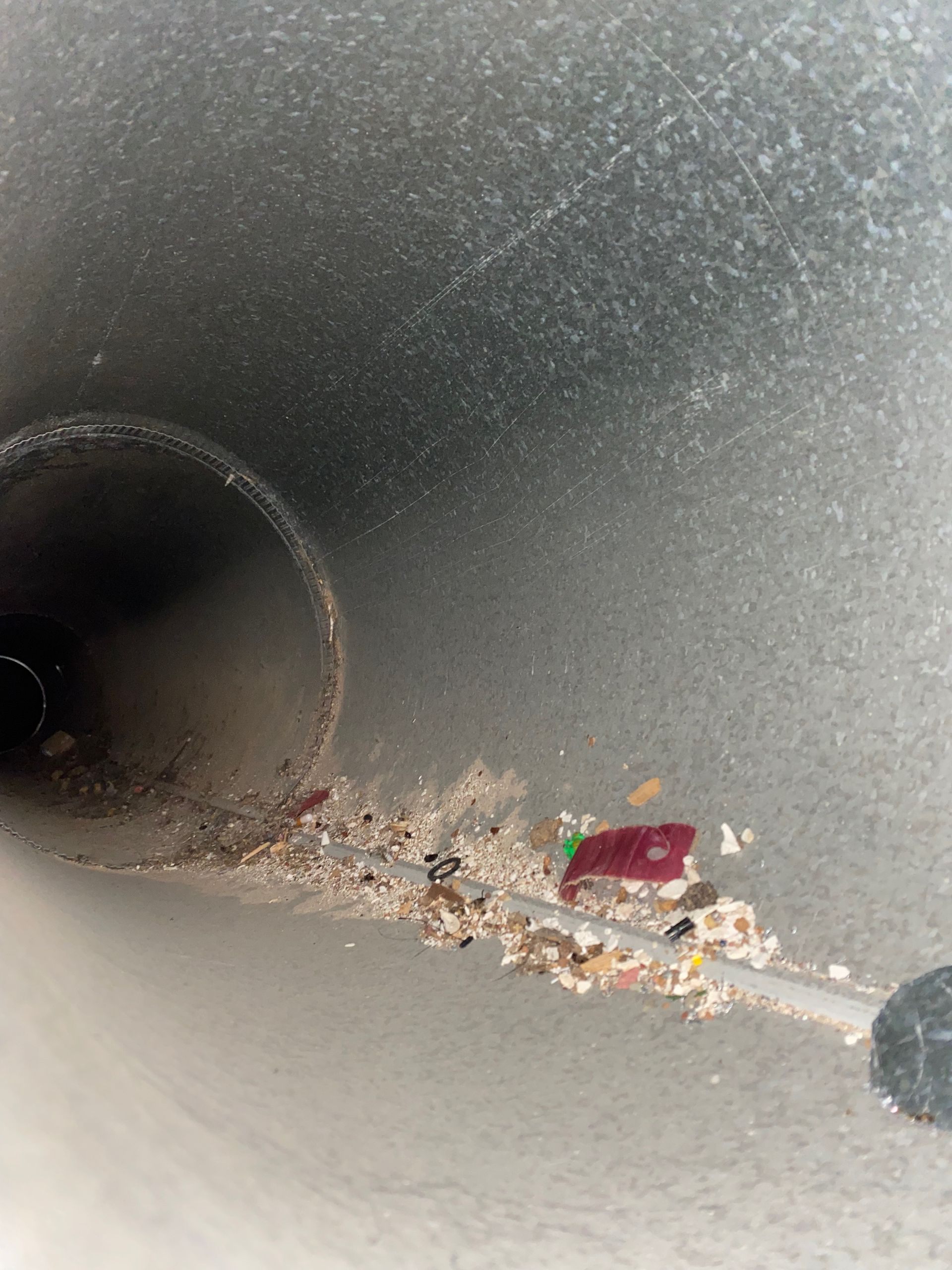 A close up of a dirty pipe with a red object in the middle