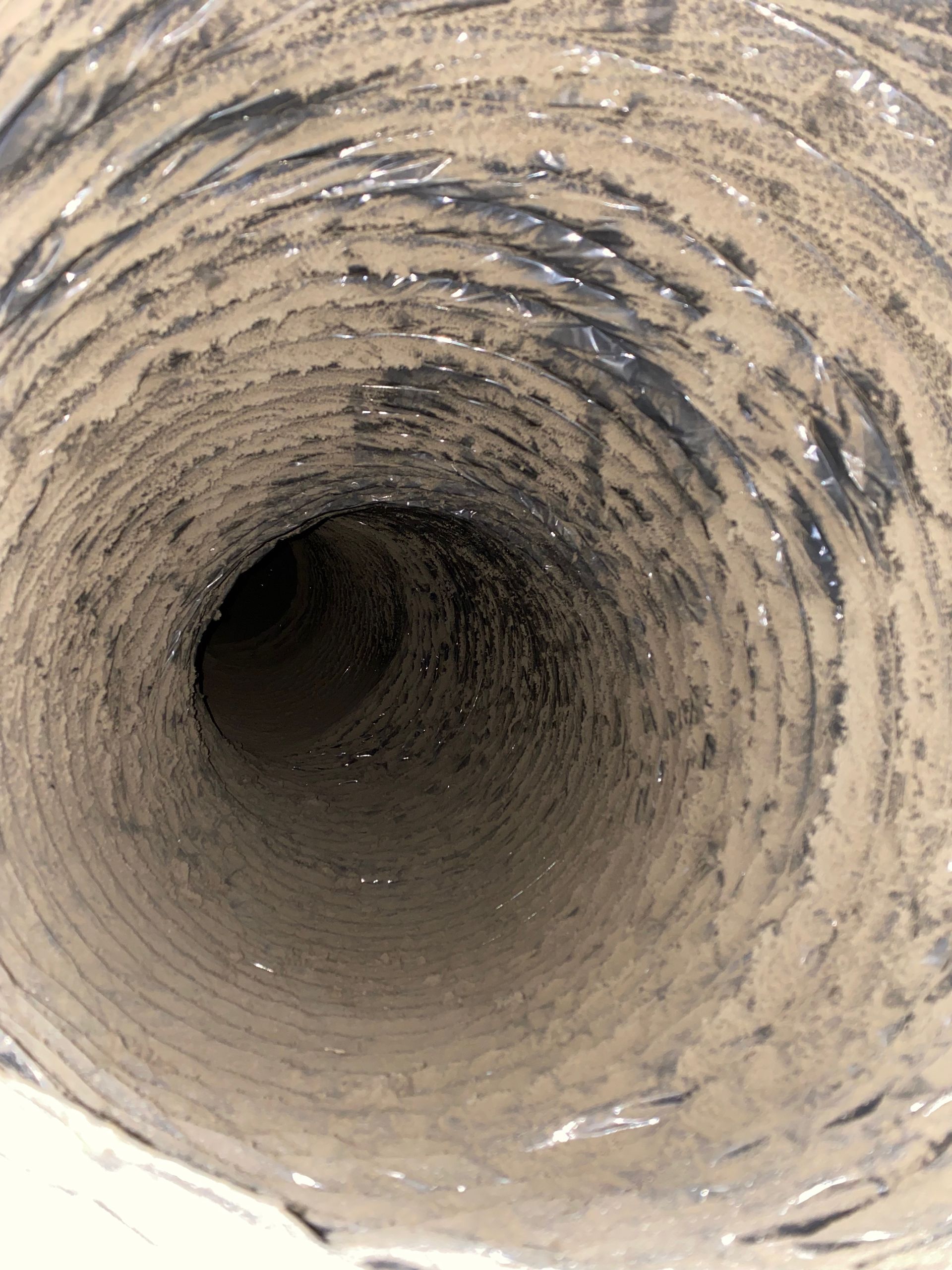 A close up of a dirty duct with a hole in the middle
