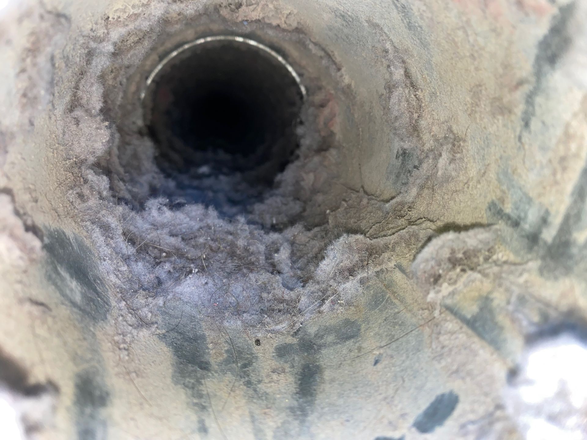 A close up of a dirty pipe with a hole in it.