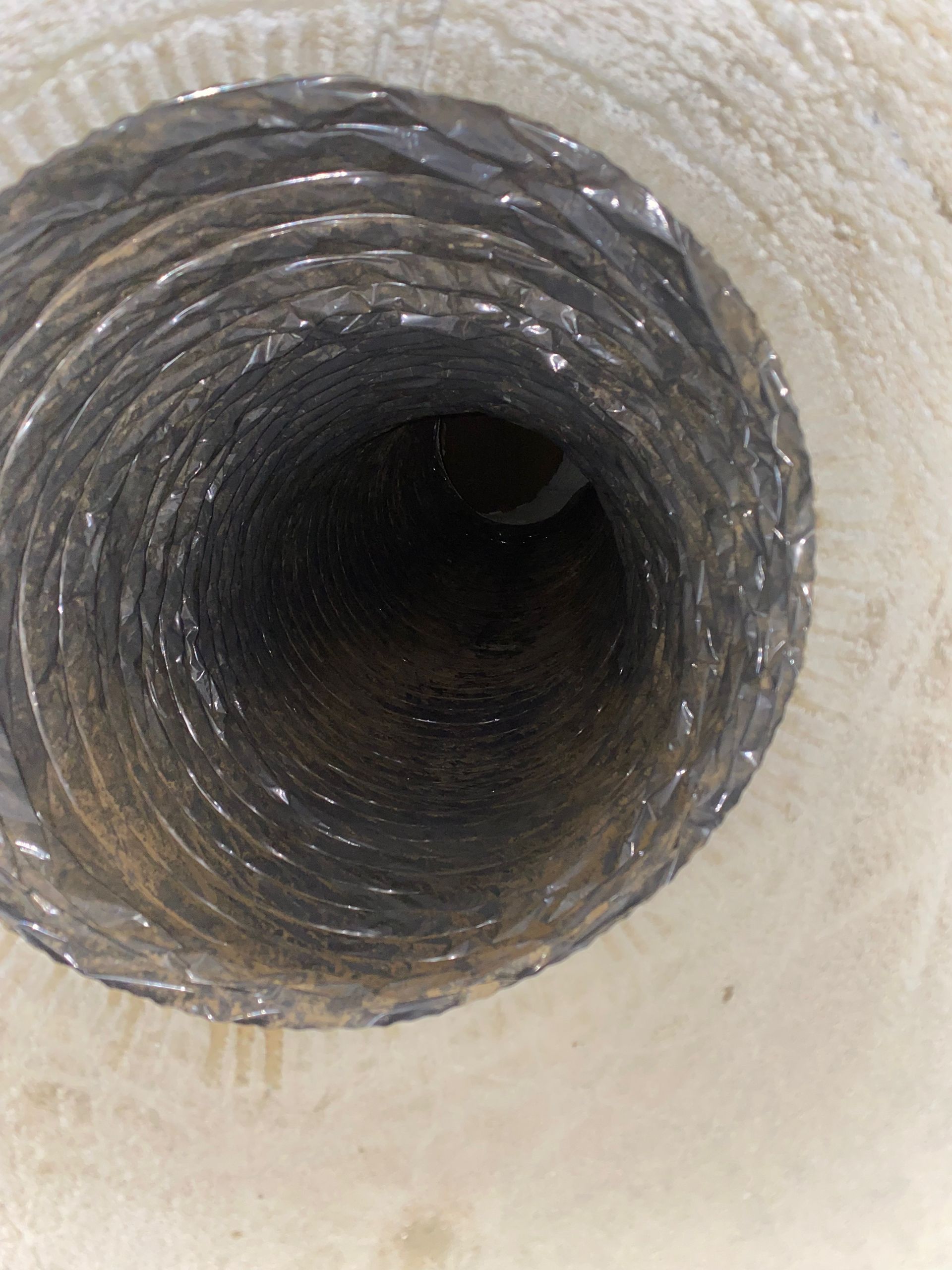 A close up of a hole in a duct on a white surface.