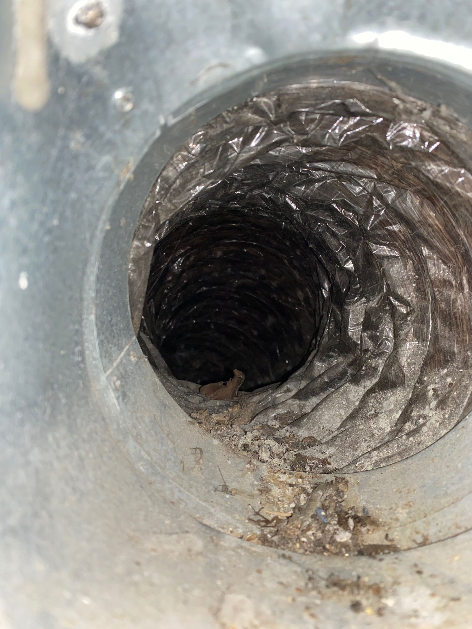 A close up of a dirty duct with a hole in it.