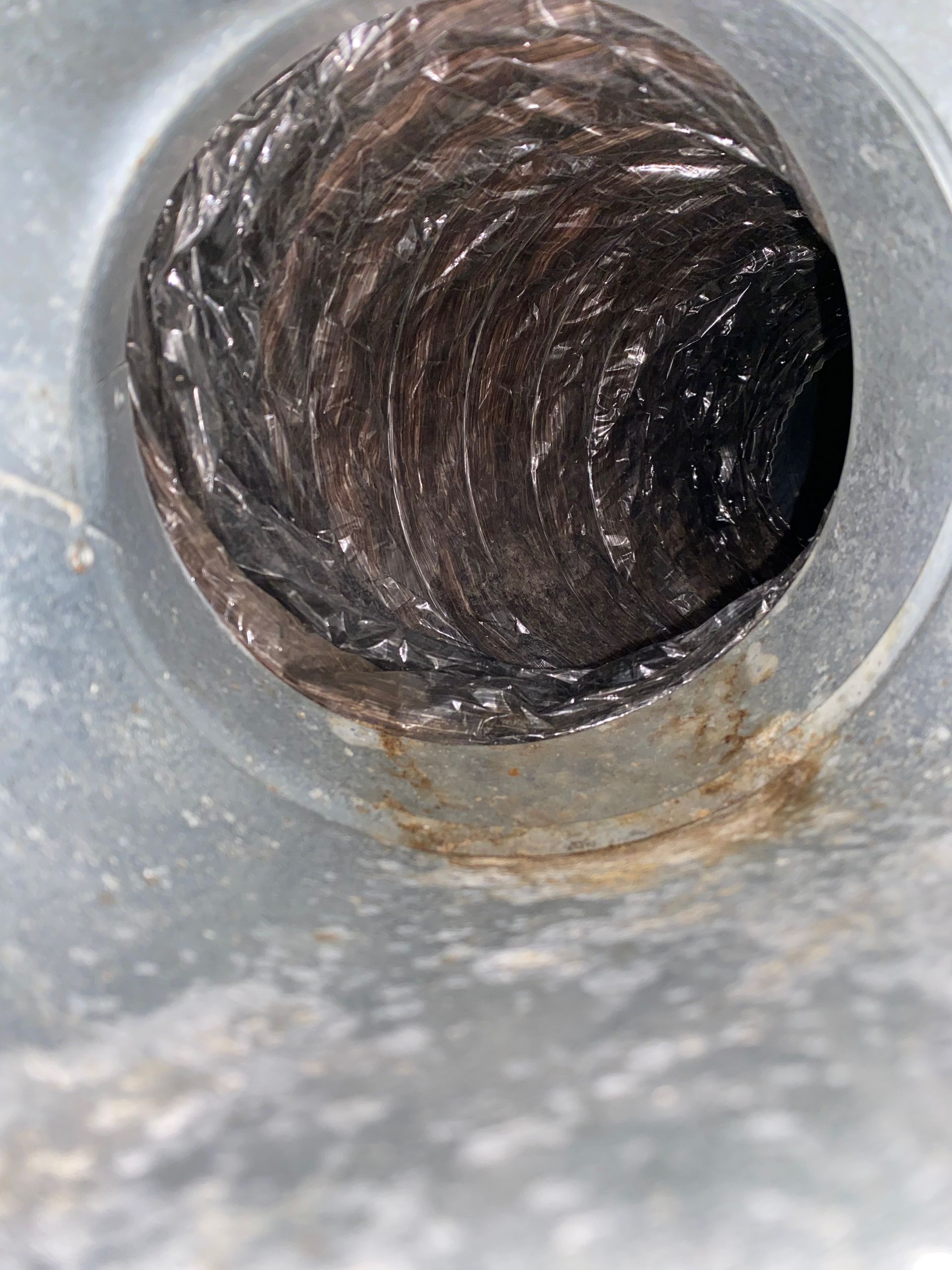 A close up of a dirty duct with a hole in it.