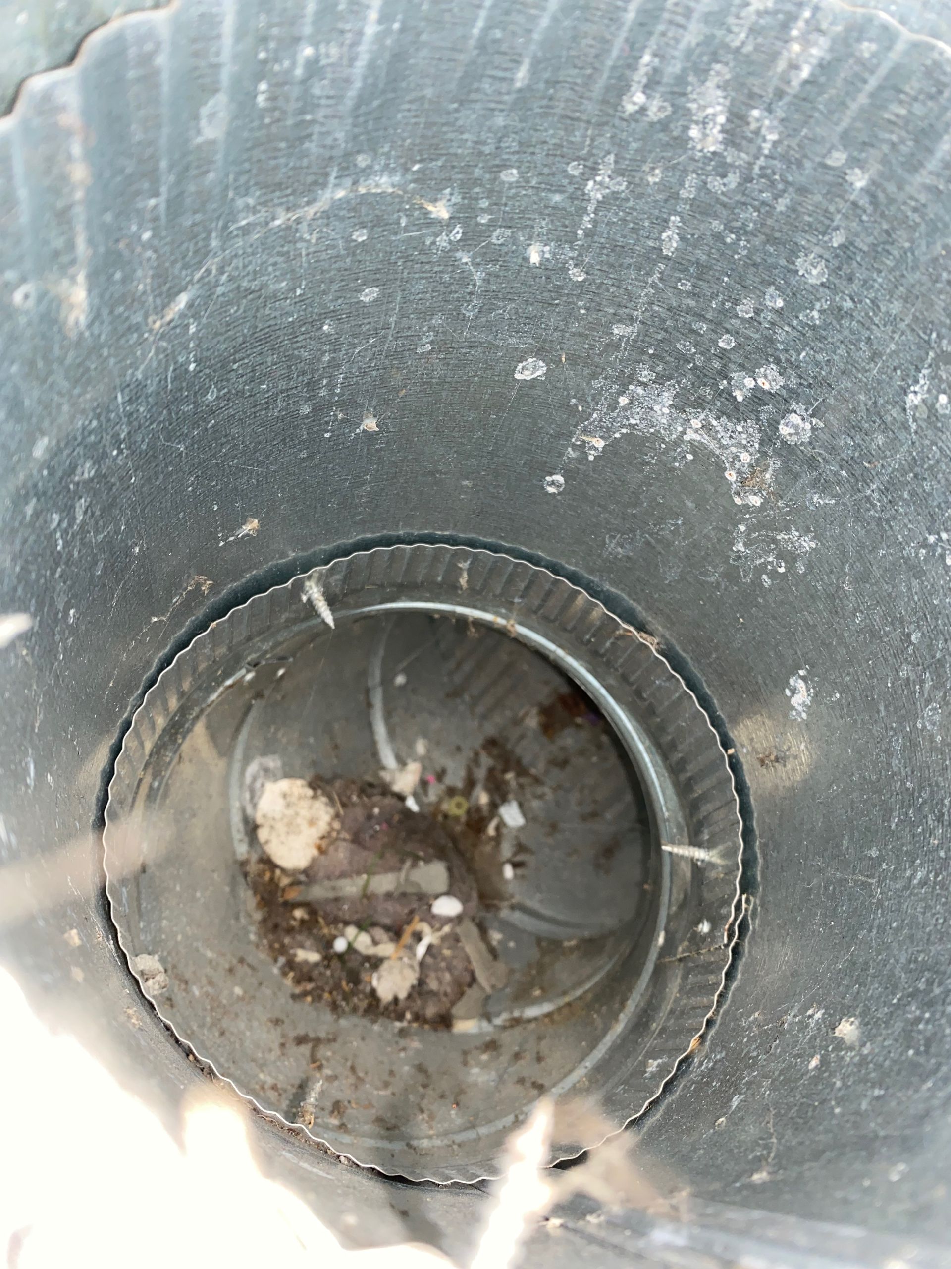 A close up of a dirty metal pipe with a hole in the middle.