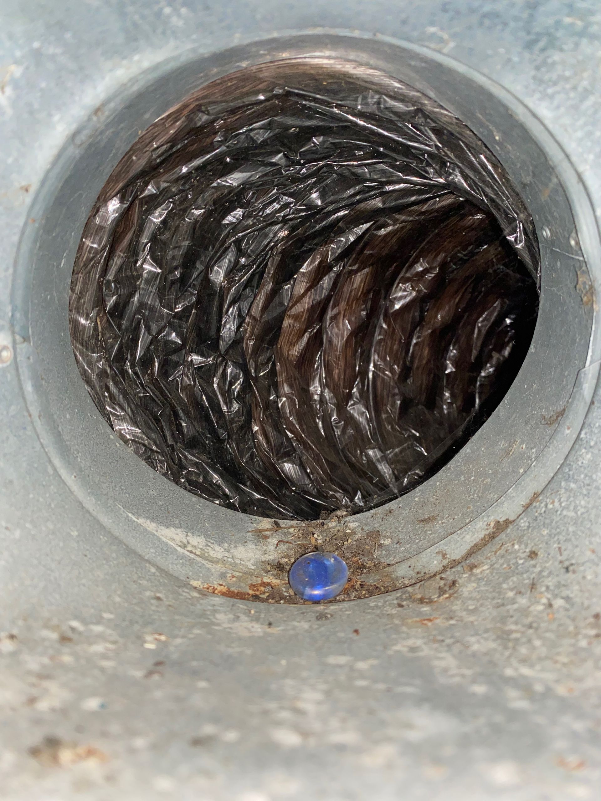 A close up of a dirty duct with a blue screw in it.