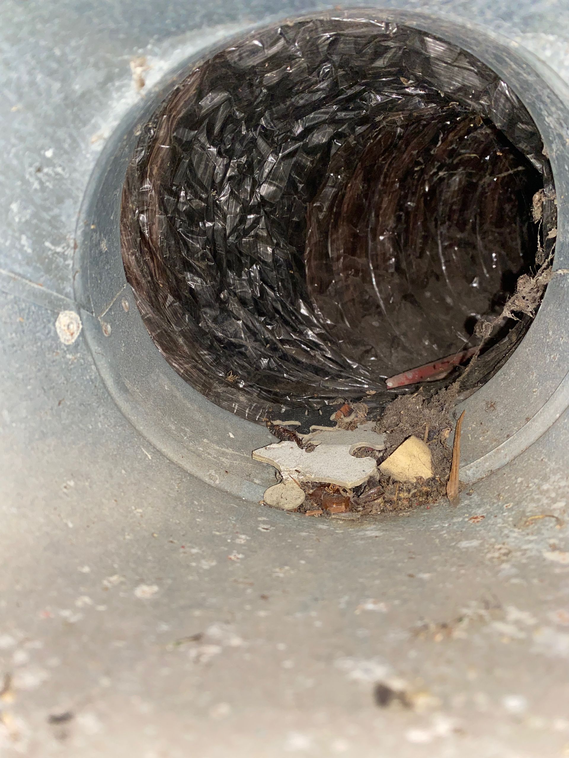 A close up of a dirty duct with a hole in it.