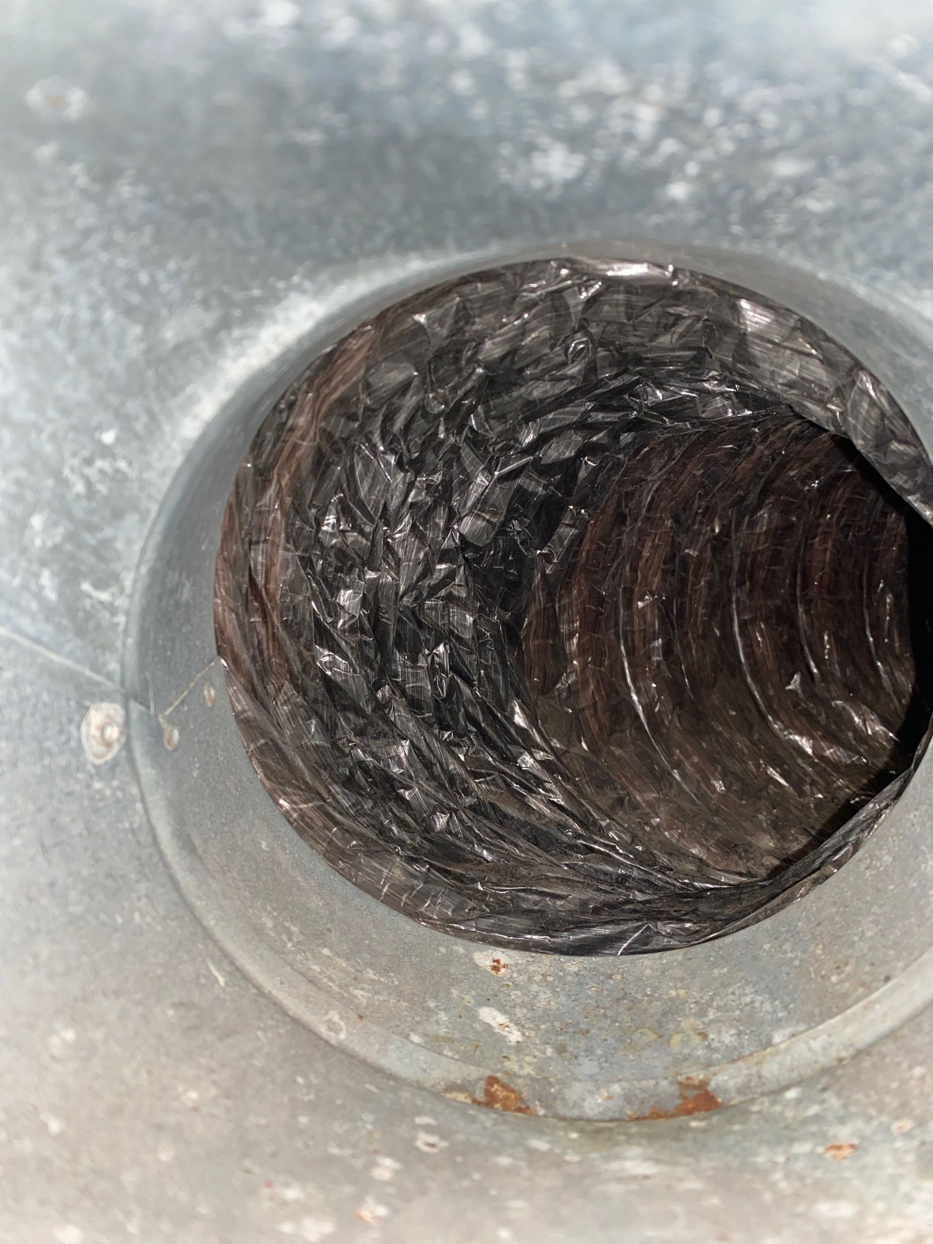 A close up of a dirty air duct with a hole in it.