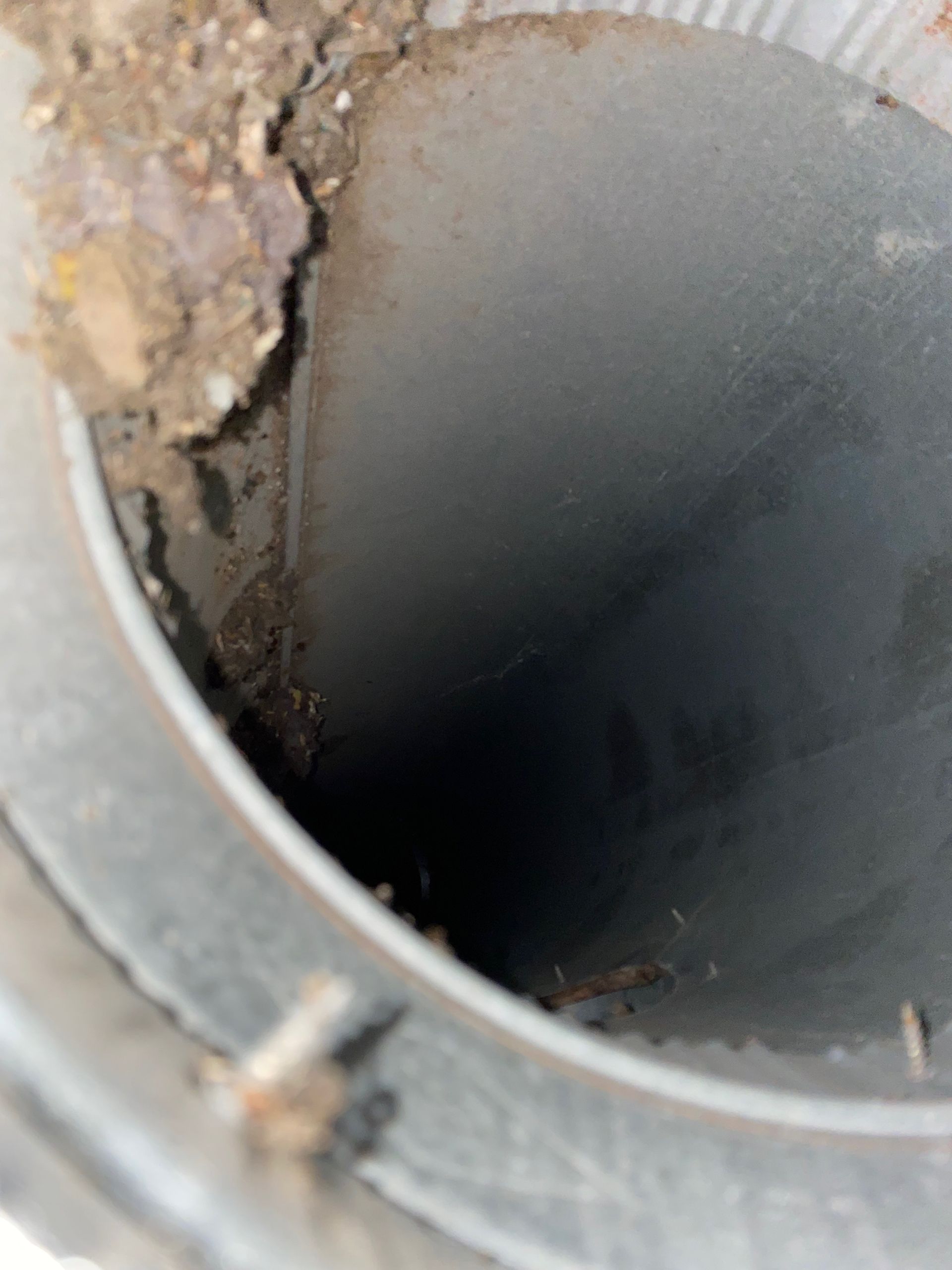 A close up of a metal pipe with dirt coming out of it.