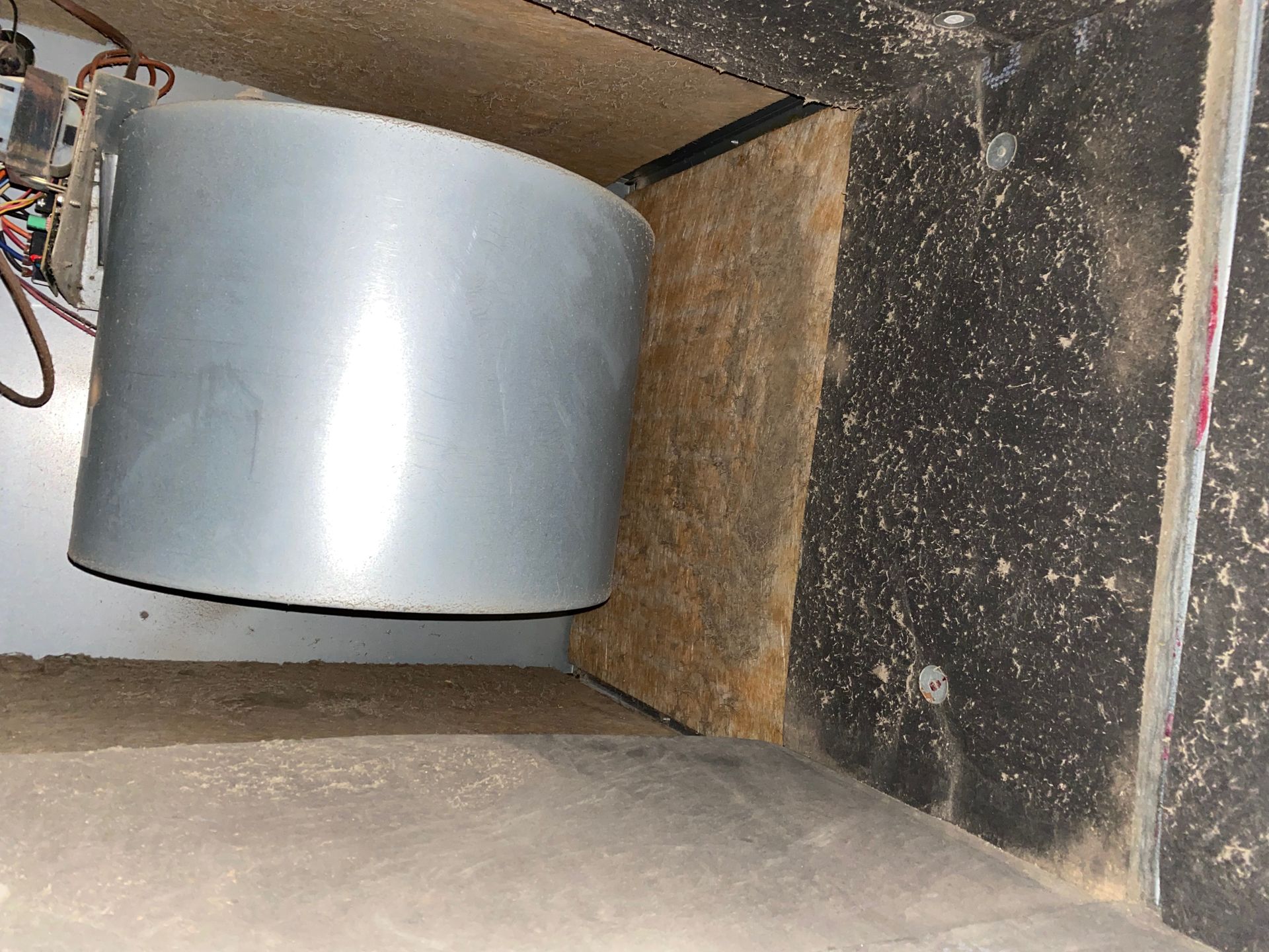 A metal cylinder is sitting in a corner of a room