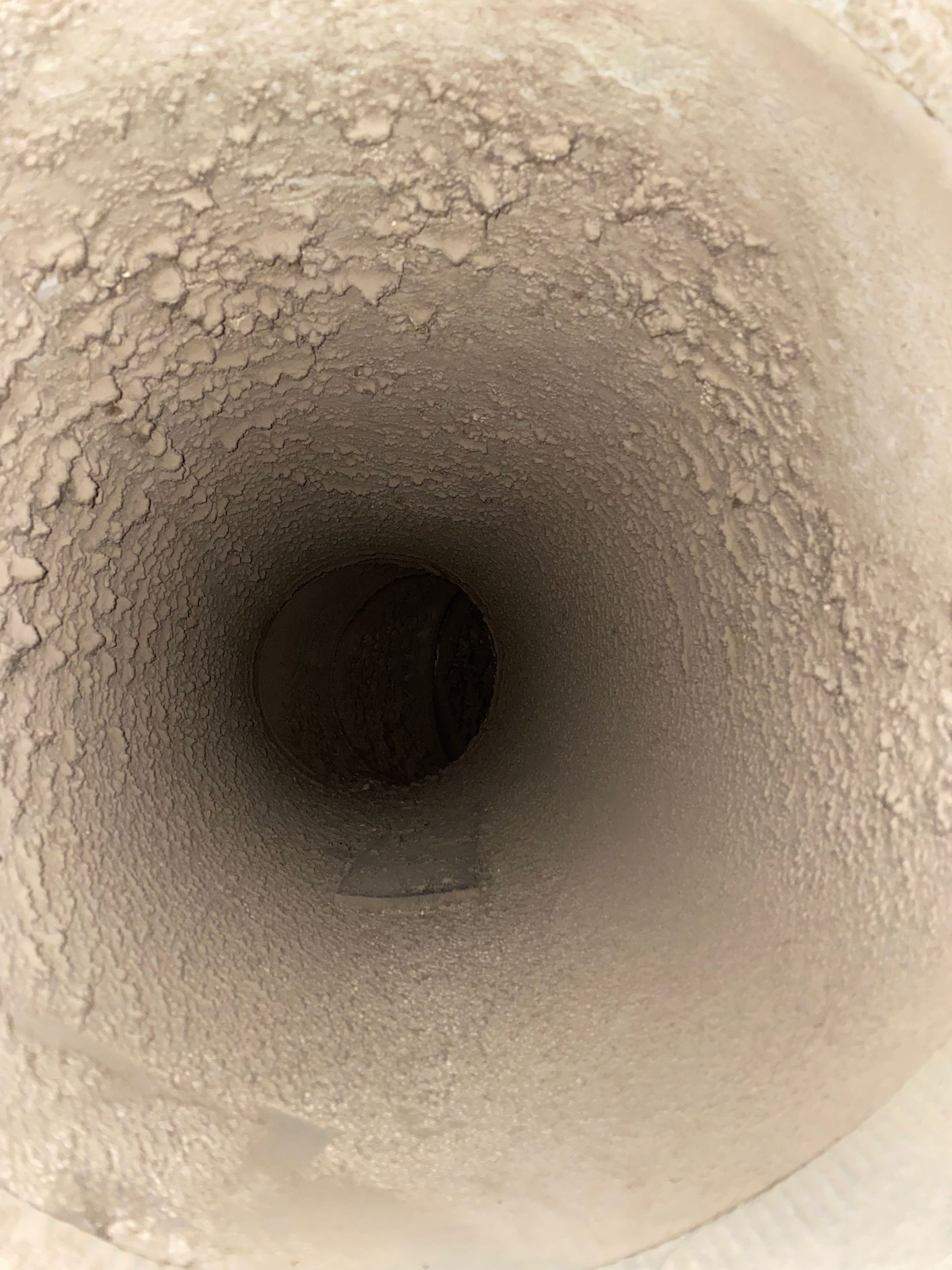 A close up of a dirty duct with a hole in the middle.