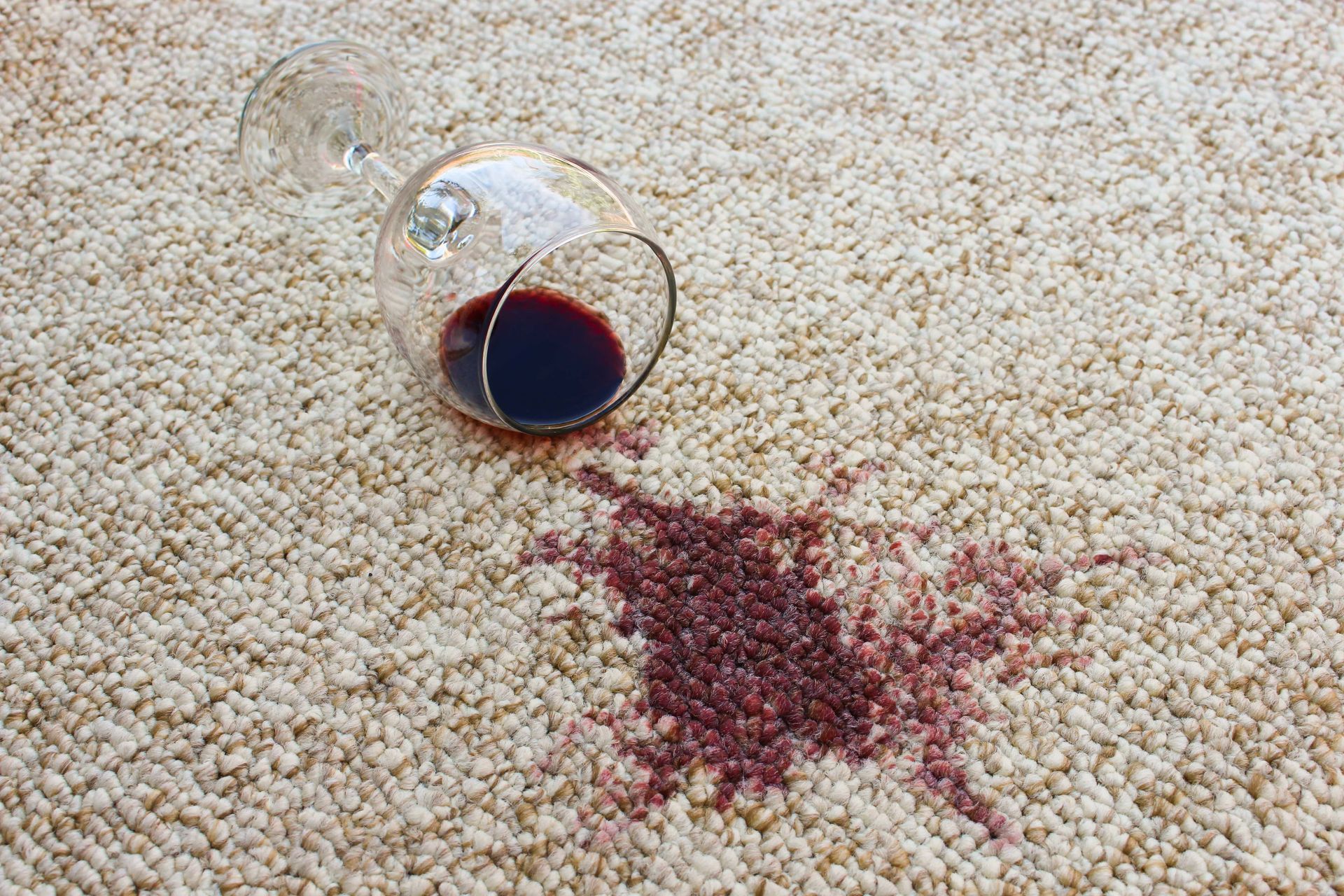A glass of red wine spilled on a carpet