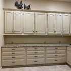 Beige kitchen with upper and lower cabinets, granite countertop, and decorative rooster figurines above the cabinets.