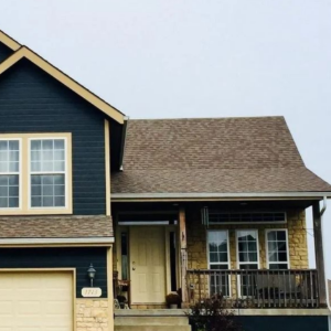 Blue two-story house with cream trim, front porch, and attached garage