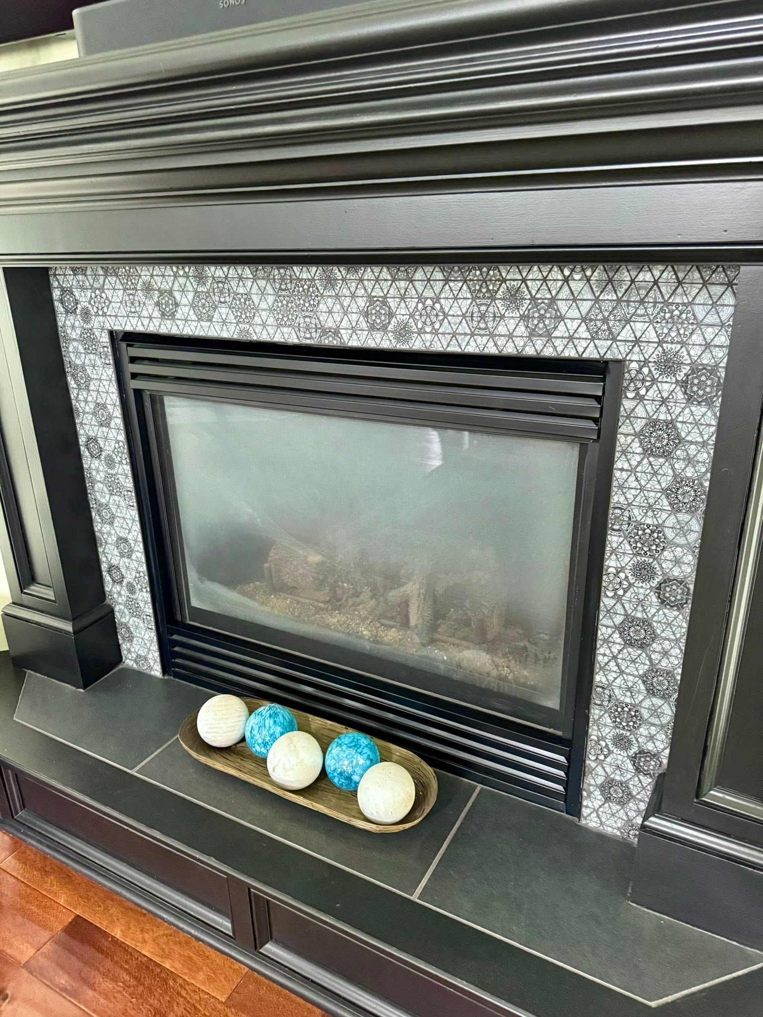 Black fireplace with frosted glass and decorative white, blue, and gold balls on the hearth