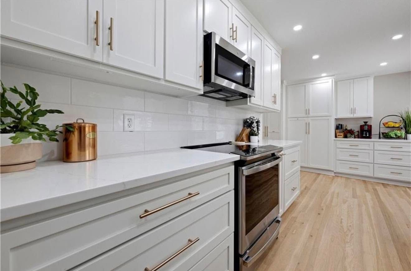 Bright white modern kitchen with stainless steel appliances and light wood floors